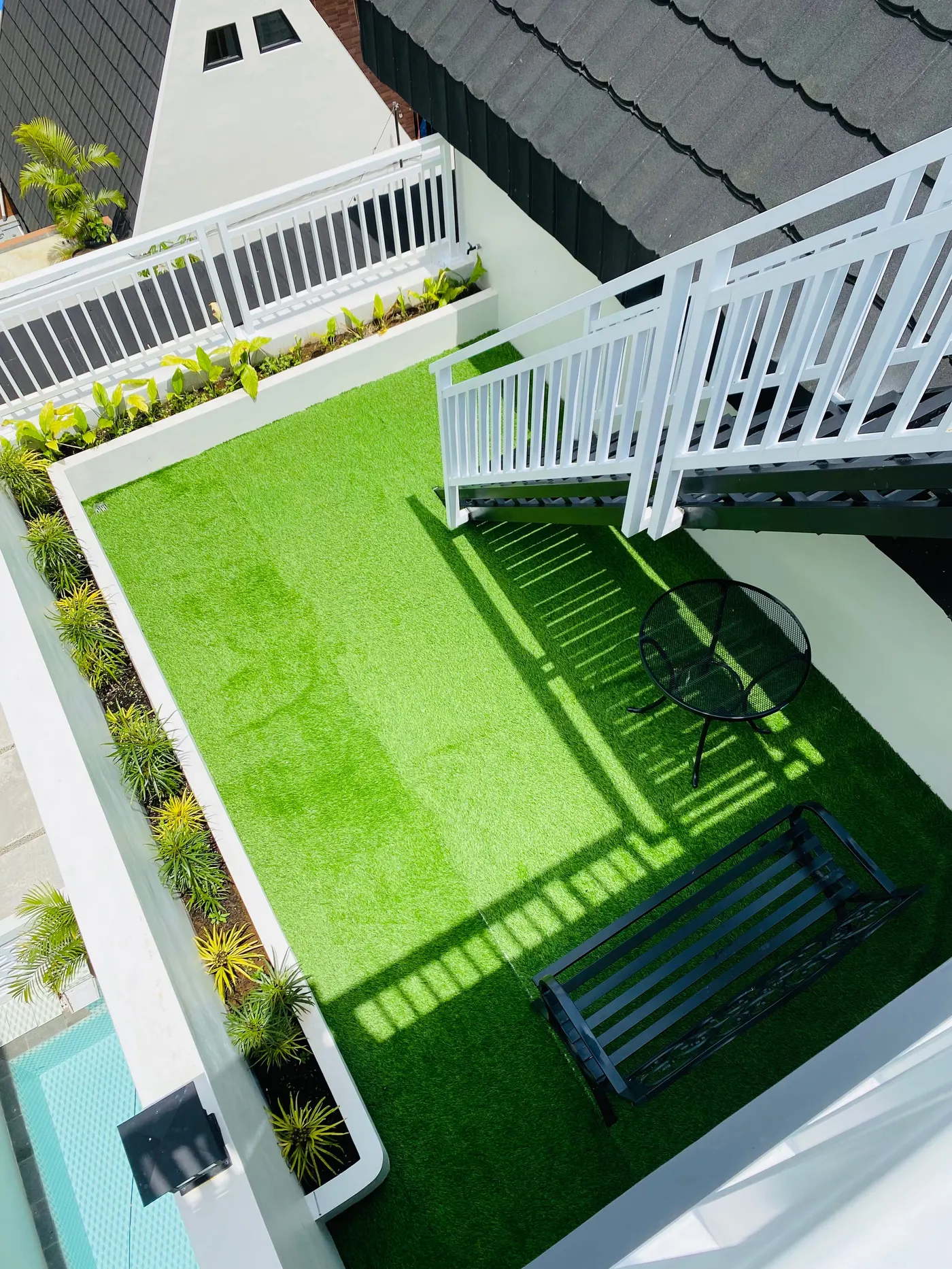Rooftop terrace covered in artificial turf with a bench and table